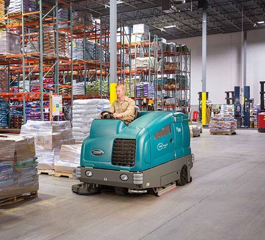 Lavapavimenti uomo a bordo industriale T20 che strofina un magazzino.
